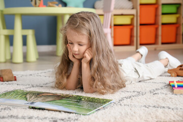 Cute little girl reading book at home