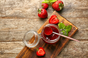 Jar of tasty strawberry jam on table