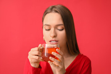 Beautiful young woman with cup of tea on color background