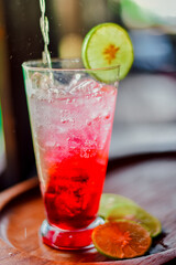 red juice water whit soda and lemon in glass on wood table at cafe. Summer  drink