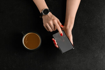 Fototapeta na wymiar Hands with beautiful manicure and mobile phone on dark background