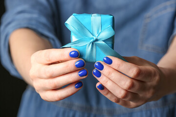 Woman with beautiful manicure holding gift, closeup
