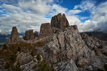 Obraz na płótnie Canvas Rugged and rocky alpine mountain ranges with cloudy blue sky above in The Dolomites. These iconic mountain peaks are located at Cinque Torri in the Tyrol region of Italy.