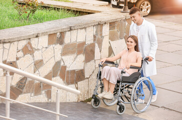 Doctor and young woman in wheelchair on ramp outdoors