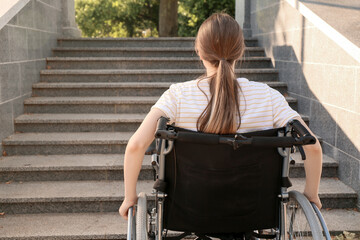 Young woman in wheelchair near stairs outdoors