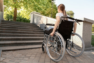 Young woman in wheelchair near stairs outdoors