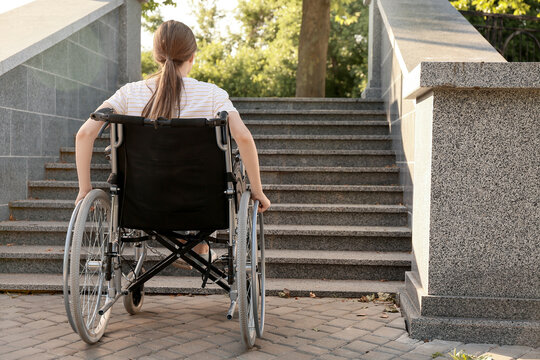 Young woman in wheelchair near stairs outdoors