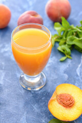 Glass of tasty peach juice on color background