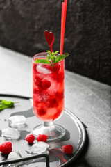 Glass of cold raspberry tea on dark background