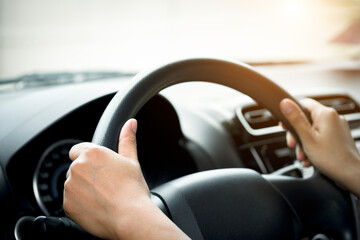 Woman's hand holding a car steering wheel,represents the correct car steering wheel. In order to...