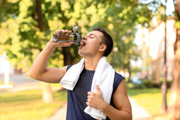 Fototapeta na wymiar Sporty young man drinking water in park