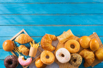 assorted junk food multiple type on blue wooden table of top view with copy space