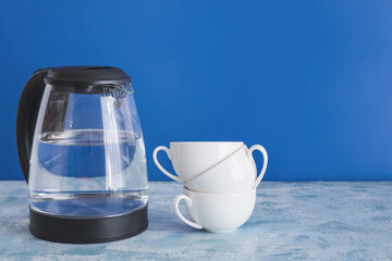 Electric kettle with cups on table