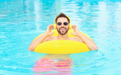 Young man listening to music in swimming pool