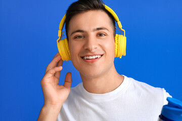 Sporty young man with headphones on color background