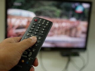 hand with the remote control television and presses the button.