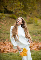 Autumn vogue. Young stylish hipster girl wearing modern dress in urban park smiling happy. Caucasian female model. Fall fashion.