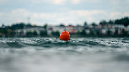 Orange buoy swimming in rippled water - obrazy, fototapety, plakaty