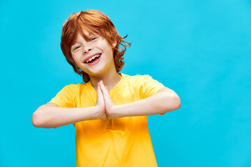 red-haired boy in a yellow t-shirt has joined hands on background and laughs