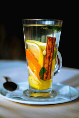 Hot tea with cinnamon bark, lemon and green leaves