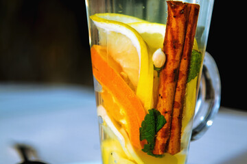Hot tea with cinnamon bark, lemon and green leaves