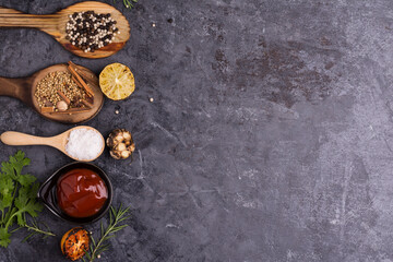 Fototapeta na wymiar Spices with lemon sauce, tomatoes garlic rosemary wooden spoon black table top Top view and there is a blank space for designing the text.