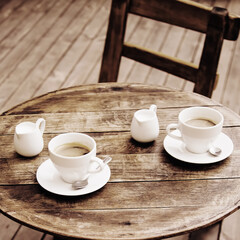 Two cups of coffee on rustic wooden table background art.