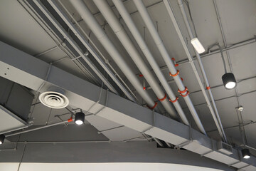 Ventilation pipes in silver insulation material hanging from the ceiling inside the new building.
