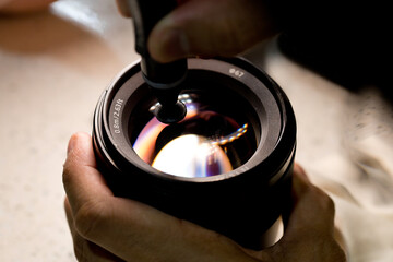 Cropped hand of male technician checking and cleaning the camera lens in the workshop. Expertise...