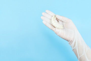Hand in white medical gloves holding  snap on teeth(Denture crown for beauty) on blue background,health care concept