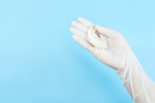 Hand in white medical gloves holding  snap on teeth(Denture crown for beauty) on blue background,health care concept