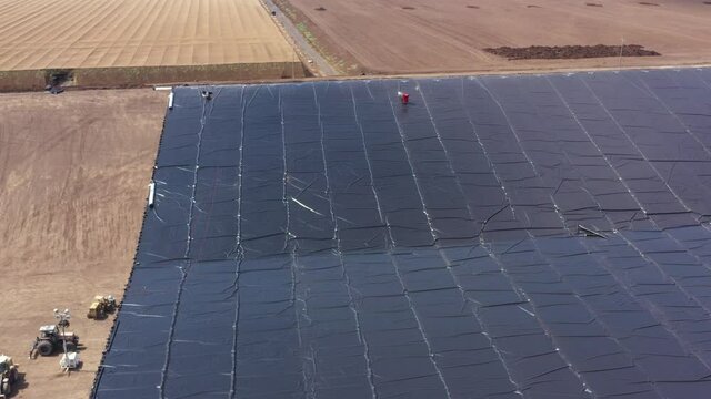 Water reservoir construction site with newly installed plastic lining sheets, Aerial view.