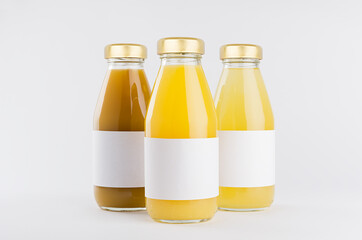 Orange, yellow fruit juices collection in glass bottles with cap, white blank labels, group mock up on white background, template for packaging, advertising, design product, branding.