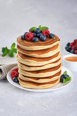 Pancakes with fresh berry and honey on gray background. Healthy breakfast.
