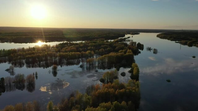 Spring. Sunset over the flooded forest. View from a drone on a flooded forest, a reflection of the sun and clouds in the water. 