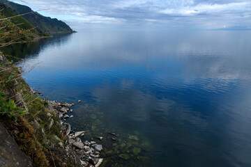 Shore of Baikal lake in summer with reflection of blue sky in water