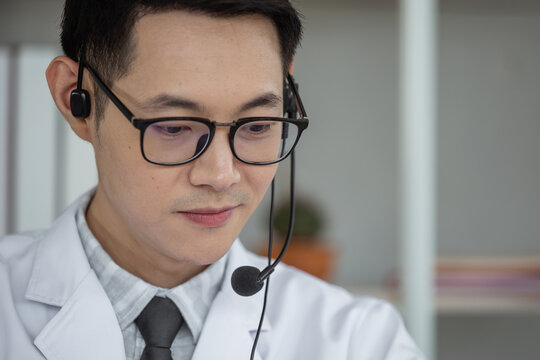 Handsome Man Doctor Speaking Microphone With Headset To Patient At Work In Home Office, Online Conference, Work New Normal.