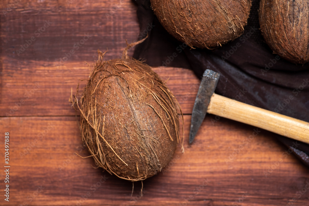 Poster open coconut and a small hammer on a wooden table top view
