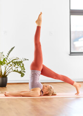 fitness, people and healthy lifestyle concept - young woman doing yoga in supported shoulderstand at home