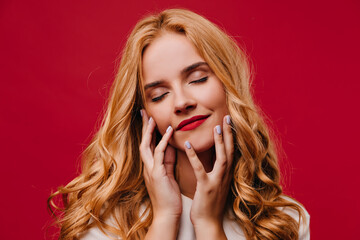 Close-up photo of magnificent white woman. Charming long-haired girl posing on red background.