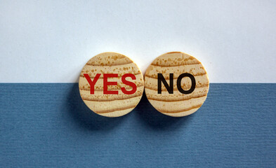 Wood circles with words 'yes, no' on paper white and blue background, copy space. Business concept.