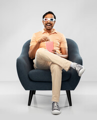 people and concept - happy smiling young indian man in 3d glasses eating popcorn and watching movie sitting in chair over grey background