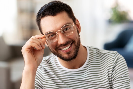 people concept - portrait of happy smiling man in glasses at home