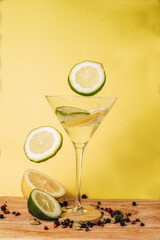 Lemonade time, lemon wedges and lime falling into a cocktail glass.