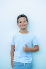 Boy in white shirt standing on white wall background