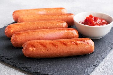 Juicy grilled meat sausages with tomato sauce and ketchup on a concrete stand. Fat fast food. Concept unhealthy eating.