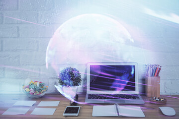 Computer on desktop in office with technology theme hologram. Double exposure. Tech concept.