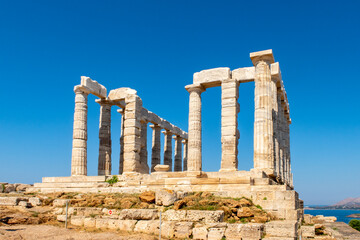 Fototapeta na wymiar The ancient Greek Temple of Poseidon at Cape Sounion, doric columns and ruins on the hill with crystal blue sky background.