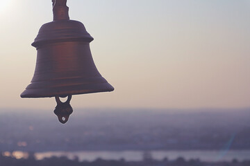 Silhouette of a bronze bell against the sky and horizon.
