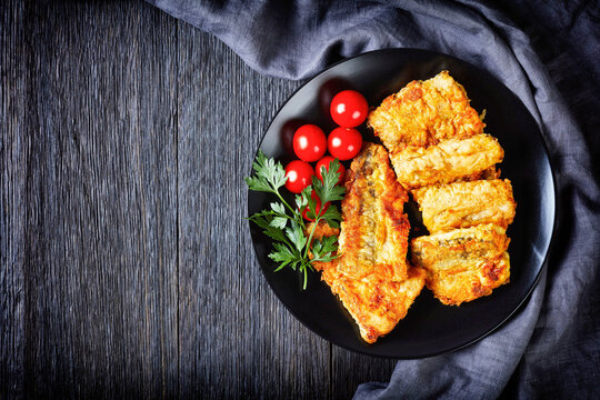 Cod fillet on black plate with cherry tomatoes
